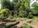 Tranquil backyard showcasing storage sheds surrounded by manicured greenery and brick walkways at 2143 Ridge Rd, Raleigh, NC 27607