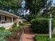 Brick walkway leading to home surrounded by mature trees and lush landscaping at 2143 Ridge Rd, Raleigh, NC 27607