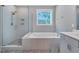 Bright bathroom featuring a glass shower, garden tub, and tiled floor at 2848 Angelica Rose Way, Apex, NC 27502