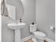 Modern powder room with pedestal sink, toilet, round mirror and neutral decor at 2848 Angelica Rose Way, Apex, NC 27502
