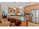 Modern kitchen featuring wooden cabinets, granite countertops, a stainless steel refrigerator, and an island with barstool seating at 30119 Settle, Chapel Hill, NC 27517