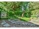 Backyard landscape with lush greenery, stone borders, and unique metal crane sculpture at 308 Rainbow Dr, Carrboro, NC 27510