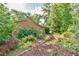 Backyard with lush foliage, stone path, and well-maintained brick home at 308 Rainbow Dr, Carrboro, NC 27510