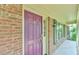 Exterior view of a plum front door framed by brick and sidelight, complemented by a black shuttered window at 308 Rainbow Dr, Carrboro, NC 27510