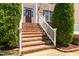 Inviting brick front porch with white railings, complemented by lush greenery and tasteful landscaping at 4404 Triland Way, Cary, NC 27518