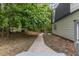 Backyard view shows mature trees and the side of the home with a walkway at 4713 Erwin Rd, Durham, NC 27705