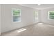 Sunlit bedroom with three windows, neutral carpet, and white walls, showcasing ample natural light at 4713 Erwin Rd, Durham, NC 27705