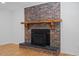 Close-up of a brick fireplace with a wood mantle and black hearth, on a light hardwood floor at 4713 Erwin Rd, Durham, NC 27705