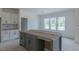 Spacious kitchen area featuring a large gray island and white cabinets, flooded with natural light from three windows at 48 Sanders Farm Dr, Smithfield, NC 27577