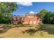 Brick home's backyard with ample lawn, staircase to a backdoor, and mature shade trees at 4813 Glen Forest Dr, Raleigh, NC 27612
