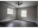An open bedroom features two windows, grey walls, hard flooring and a ceiling fan at 4813 Glen Forest Dr, Raleigh, NC 27612