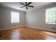 Cozy bedroom with hardwood floors, ample natural light from two windows, and a ceiling fan at 4813 Glen Forest Dr, Raleigh, NC 27612