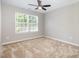 This bedroom features neutral walls, carpet flooring, a ceiling fan, and a large window at 5416 Kissimmee Ln, Raleigh, NC 27616
