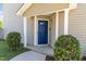 Inviting entryway with a blue front door, white pillars, and manicured bushes at 5416 Kissimmee Ln, Raleigh, NC 27616
