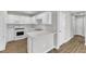Kitchen featuring white cabinets, white appliances, LVP floors, and a breakfast bar at 5420 Roan Mountain Pl, Raleigh, NC 27613
