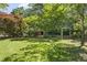 Large, grassy backyard with mature trees and foliage featuring an outdoor pergola at 5517 Spring Rd, Raleigh, NC 27603