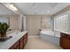 Relaxing bathroom with a soaking tub, an art piece, a wooden vanity with a large mirror and tile flooring at 606 Churton Grove Blvd, Hillsborough, NC 27278