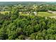 Wide aerial perspective showcasing the home's location amidst serene wooded areas and manicured fields at 61 Stone Ledge, Pittsboro, NC 27312