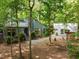 Beautiful exterior featuring a quaint home nestled among mature trees, American flag and inviting curb appeal at 61 Stone Ledge, Pittsboro, NC 27312