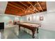 Finished basement with a pool table, exposed wood beams, and a painted brick accent wall at 612 Swift Ave, Durham, NC 27701