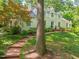 Charming home with brick pathway leading to the entrance, surrounded by lush greenery and mature trees at 612 Swift Ave, Durham, NC 27701