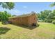 A brick home with fenced backyard and an external air conditioning unit surrounded by a green lawn and trees at 714 W Mckinley St, Mebane, NC 27302
