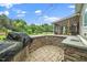 Outdoor kitchen with stone surround, built in grill, sink, stone patio and outdoor string lights at 7805 Tuscan Ridge Dr, Wendell, NC 27591