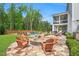 Extensive backyard with a stone fire pit, in-ground pool, outdoor patio dining, and covered porch, surrounded by trees at 808 Wimberly Rd, Apex, NC 27523