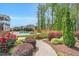 A beautifully landscaped backyard with a pool and stone fire pit area, surrounded by lush greenery and vibrant red flowers at 808 Wimberly Rd, Apex, NC 27523