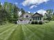 Expansive backyard featuring a well-maintained lawn, deck, and exterior of the beige two-story home on a sunny day at 84 Macbeth Ln, Roxboro, NC 27574
