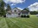 Expansive backyard featuring a well-maintained lawn, deck, and exterior of the beige two-story home on a sunny day at 84 Macbeth Ln, Roxboro, NC 27574