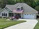 Charming one-story home with manicured lawn, two-car garage, and front porch with chairs and a jet ski at 84 Macbeth Ln, Roxboro, NC 27574