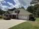 Exterior view of a charming home with a well-manicured lawn, a two-car garage, and a covered porch at 84 Macbeth Ln, Roxboro, NC 27574