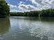 Scenic lake view with serene waters, surrounded by lush trees and blue skies with clouds at 84 Macbeth Ln, Roxboro, NC 27574