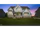 Charming two-story home featuring stone accents, gabled roof, and a well-manicured lawn at dusk at 8416 Brady Pointe Rd, Fuquay Varina, NC 27526