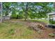 Large lot with grass and a wood shed nestled among trees, with stacked logs in the foreground at 1012 Rainey St, Burlington, NC 27217
