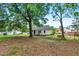 A cozy white cottage features a spacious backyard with mature shade trees and a small patio area at 1012 Rainey St, Burlington, NC 27217