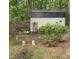 Backyard shed surrounded by lush greenery, garden ornaments, and charming rose bushes at 102 Kipling Dr, Oxford, NC 27565