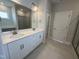 Bathroom with dual sink vanity, tiled floors, framed mirror, and shower in the background at 1033 Bostonian Dr, Knightdale, NC 27545
