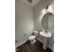 Well-lit powder room featuring dark wood floors, a pedestal sink, and an oval mirror at 1033 Bostonian Dr, Knightdale, NC 27545