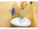 Clean and simple powder room featuring a pedestal sink and round mirror at 1220 Canyon Rock Ct # 107, Raleigh, NC 27610
