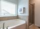 Bright bathroom with a separate glass enclosed shower and large soaking tub by a bright window at 1314 Cornell Pl, Raleigh, NC 27607