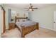 Comfortable bedroom features a large wooden bed frame, carpet, a ceiling fan, and soft natural light at 187 Ashley Woods Ct, Clayton, NC 27527