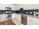 Well-lit kitchen with stainless steel appliances, granite counters, and stylish tile backsplash at 187 Ashley Woods Ct, Clayton, NC 27527