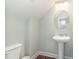Charming powder room featuring a pedestal sink, wood-look flooring, and a round mirror above the sink at 187 Ashley Woods Ct, Clayton, NC 27527