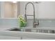Close up of sink, brushed metal faucet, white countertop, and blue glass tile backsplash at 20 Meadowcrest Dr, Durham, NC 27703