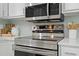 Close up of stainless steel oven range and microwave with white cabinets and countertops at 20 Meadowcrest Dr, Durham, NC 27703