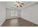 Bright, airy bedroom features a ceiling fan, tray ceiling, and a window overlooking the lush greenery at 204 Trevor Ridge Dr, Holly Springs, NC 27540