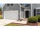 Inviting entrance with a black front door, gray siding, and manicured landscaping at 204 Trevor Ridge Dr, Holly Springs, NC 27540