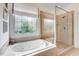 Luxurious bathroom featuring a soaking tub, separate glass shower, and stained glass window for added privacy at 233 Hein Dr, Clayton, NC 27527